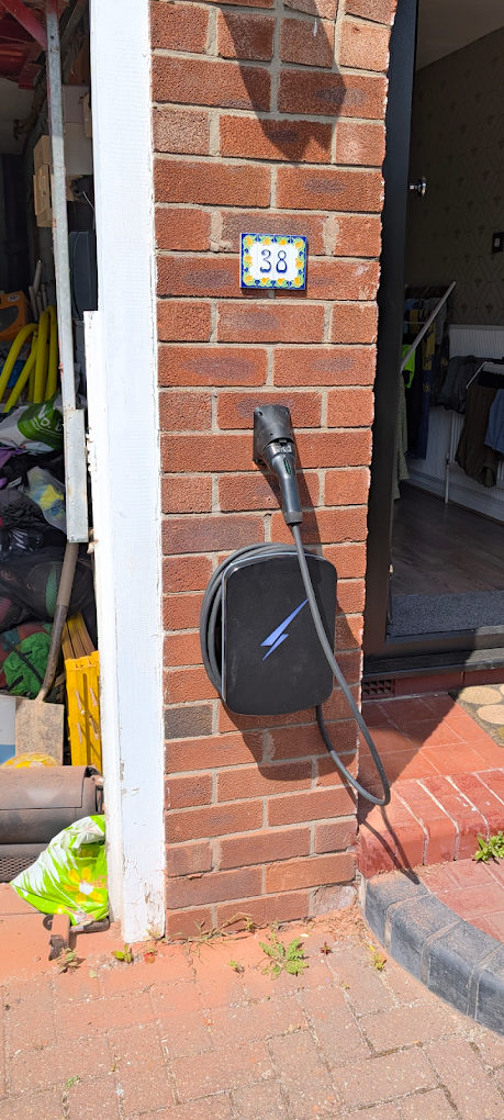EV charger and cable holster mounted on a brick pillar beside a garage