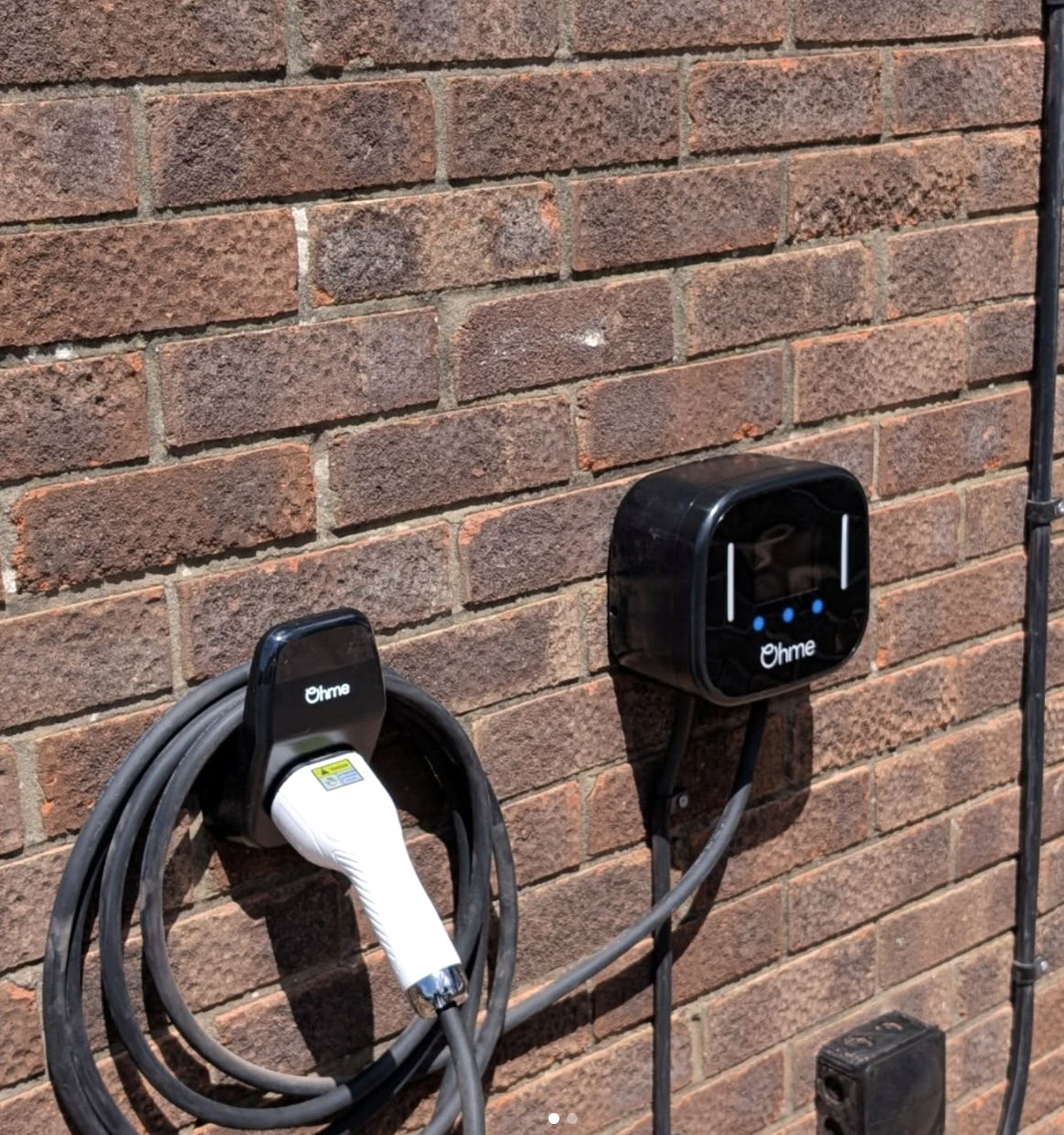 Ohme EV charger and holstered connector installed on a brick wall