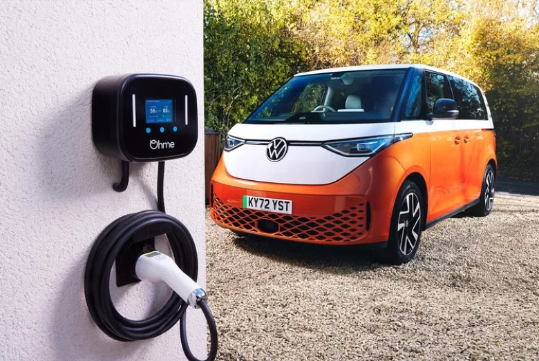 Ohme home EV charger on a white house wall with an electric van parked alongside on the driveway